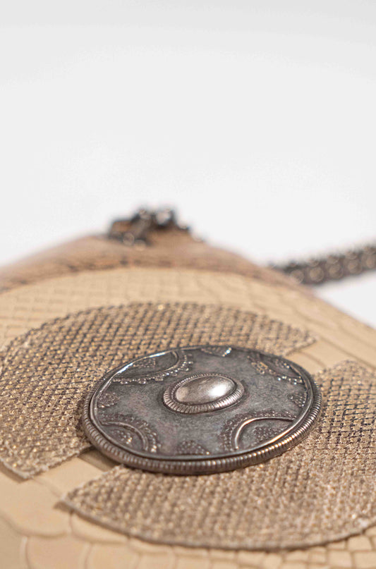 Close-up of the silver medallion and impressive handcrafted pattern on the white leather bag.