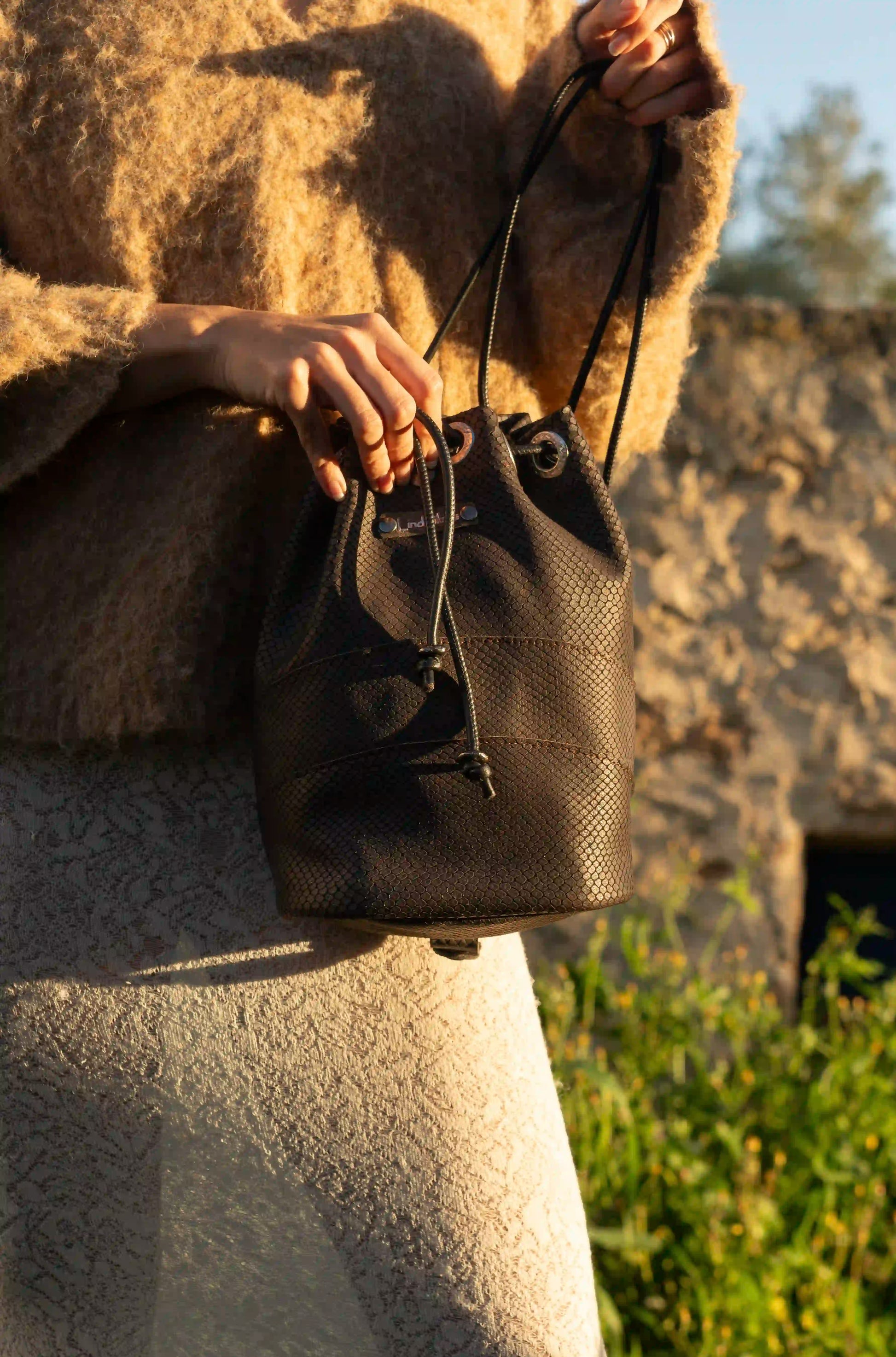 Woman wearing the premium brown leather bag as a backpack, showcasing its 3-in-1 handcrafted design in Ibiza.