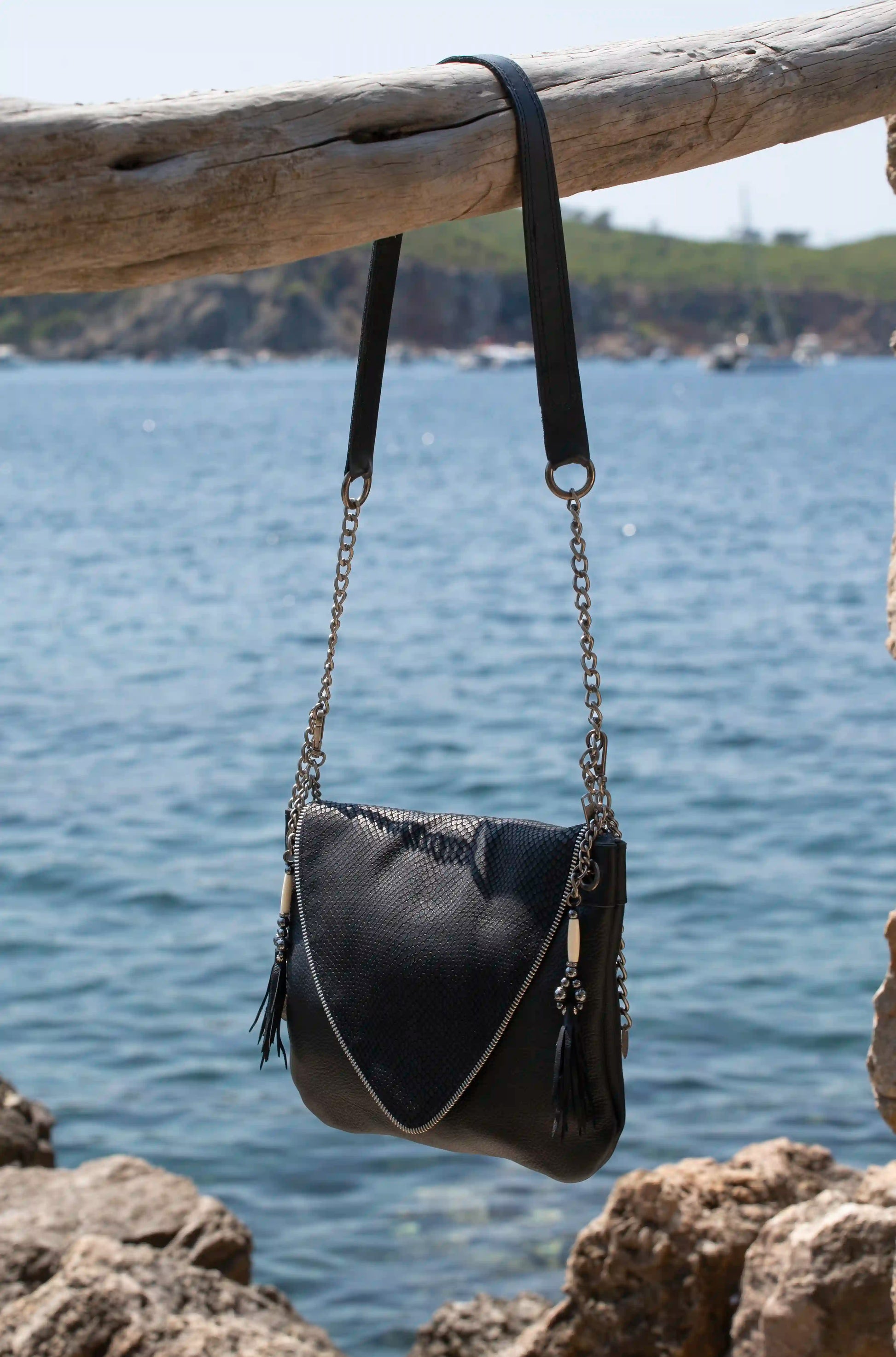 Woman wearing an artisanal black leather bag with silver chain strap and unique snake texture, a sophisticated boho-chic accessory handmade in Ibiza.