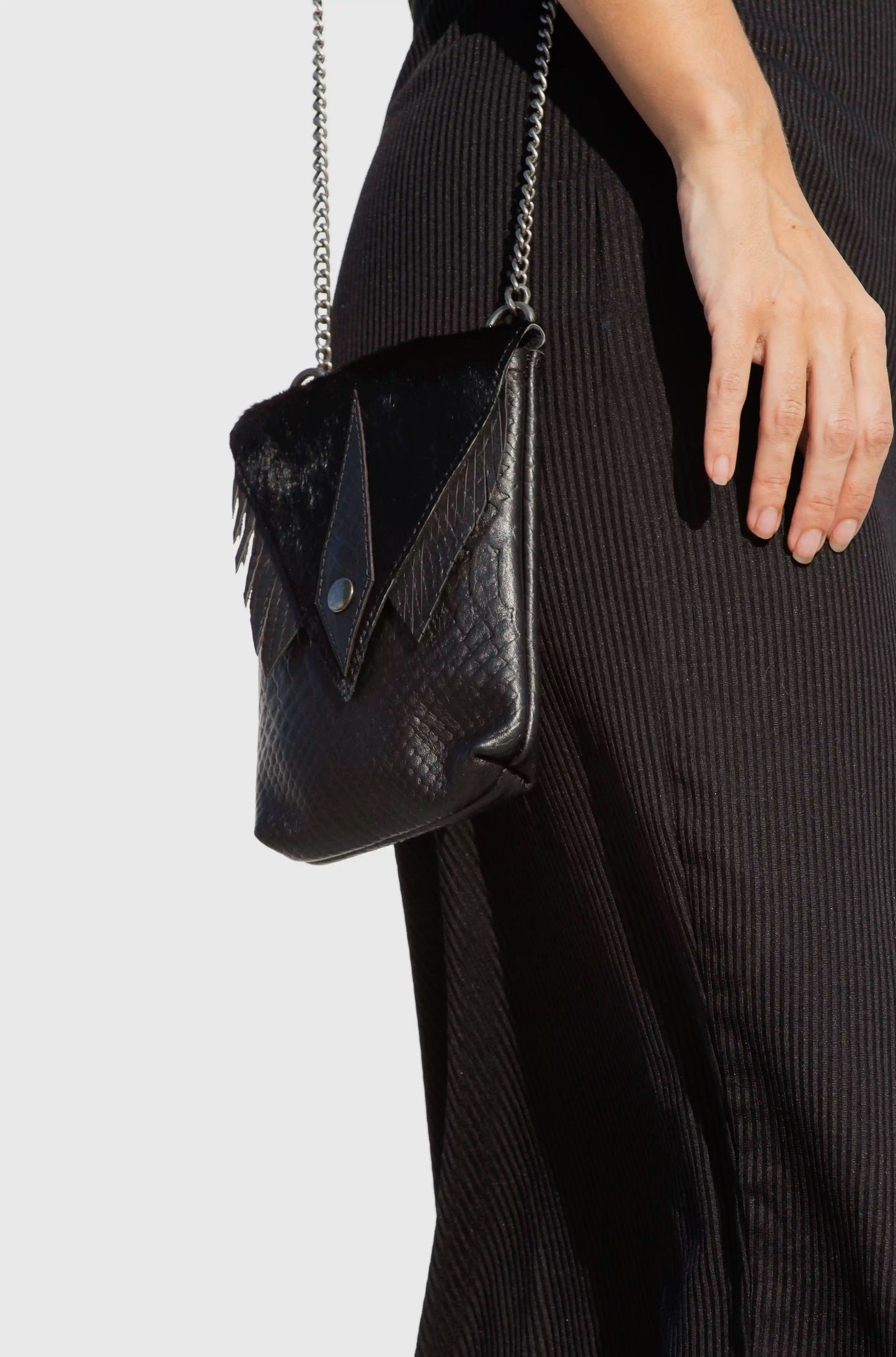 Woman wearing a premium black artisanal leather small bag with chain strap, a sophisticated boho-chic accessory handmade in Ibiza.